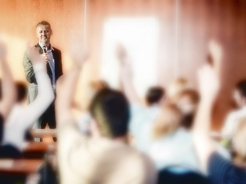 Rear View of Adult Students Raising Hands on Seminar 000051262706 Large