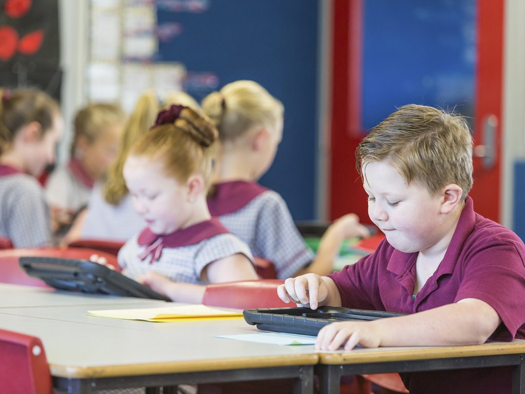 School Boy Using A Tablet Computer In The Classroom 000068941167 Medium